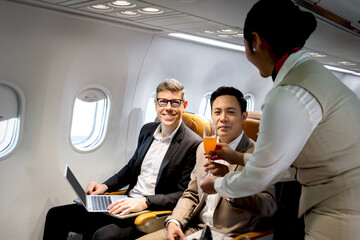 Businessman in comfortable seat inside airplane, female cabin crew air hostess serving orange juice...