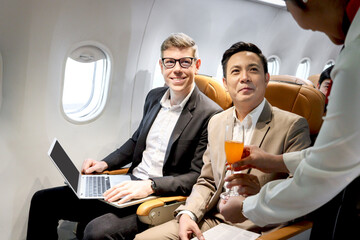 Businessman in comfortable seat inside airplane, female cabin crew air hostess serving orange juice...