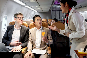 Businessman in comfortable seat inside airplane, female cabin crew air hostess serving orange juice...