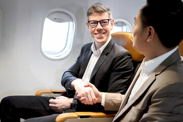 Businessman making handshake in comfortable seat inside airplane male passenger handshaking after...