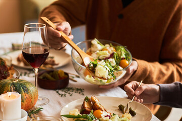 Closeup of unrecognizable man serving hearty homemade dish at dinner table with friends and family, copy space