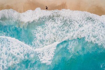 Surfer walk on sandy beach with blue ocean and waves. Aerial view - 650714351
