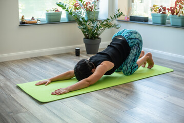 Peaceful ethnic woman practice yoga, breathing and meditating at home. Mental health, time for...