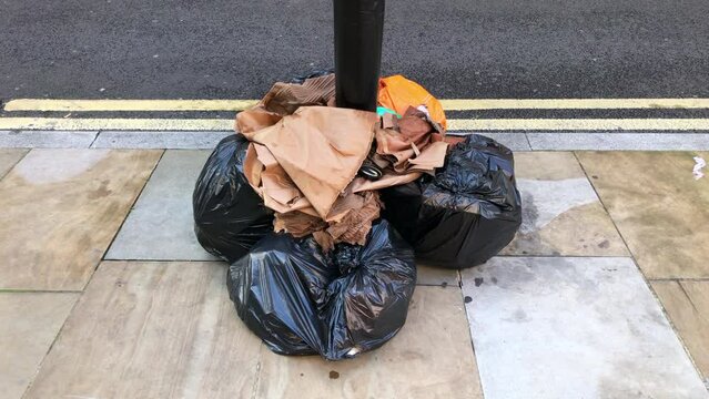 Black bin bags and waste not collected due to a council waste service strike. Concept, Bin strike, rubbish overflow refuse collection and pay dispute. Static shot.