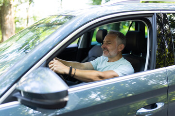 Mid adult man feeling comfortable sitting on driver seat in his new car.