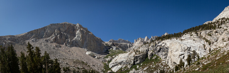 Panorama view white granite stone of Mount Whitney, trees and blue sky, usa