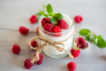 Cooked homemade yogurt with ripe red raspberries in a glass.
