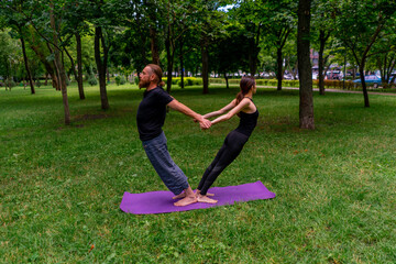 couple in love or yoga instructor and woman doing exercises in city park asana spiritual practice healthy body stretching for muscles