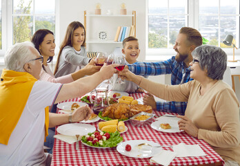 Family toast. Joyful friendly multigenerational family clinking wine glasses during Thanksgiving...