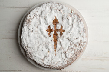 The Tarta de Santiago is the most typical sweet of Galician cuisine and is easily recognized by its emblematic Cross of Santiago in the center. - obrazy, fototapety, plakaty