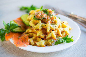 Cooked potato waffles with lightly salted red fish and herbs in a plate.