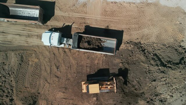 Drone wide footage. A bulldozer levels a plot of land for construction development. Above shot