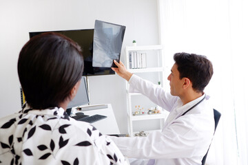 Doctor and patient look at bone x-ray film.