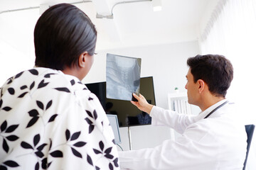 Doctor and patient look at bone x-ray film.