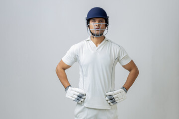 portrait of indian Man in cricket dress with helmet and gloves. Cricketer portrait in studio light looking towards the camera