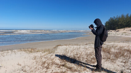 Photographer taking picture on the beach with dunes in the background