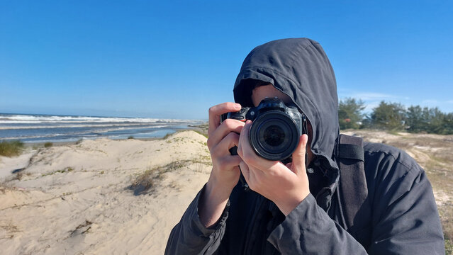 Photographer taking picture on the beach with dunes in the background