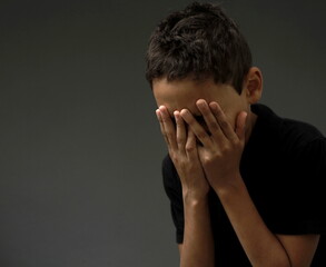 Fototapeta premium boy crying all alone by himself with grey background with people stock photo 