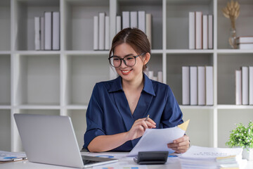 A business woman sits and examines tax documents and inspects corporate operations with a smile on her face.