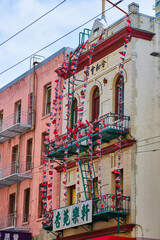 Fototapeta premium Fire escape covered in string of American and Chinese flags on white brick building