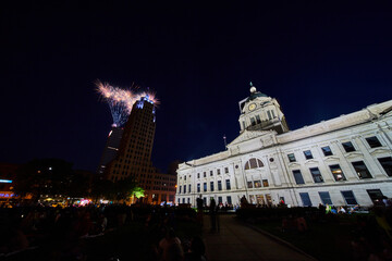 Naklejka premium Fireworks at night behind Lincoln Tower with people crowding courthouse lawn downtown Fort Wayne