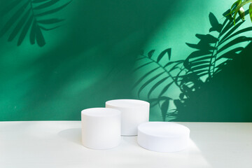 Minimal modern white product display on deep green background with white podium and palm shadow overlay