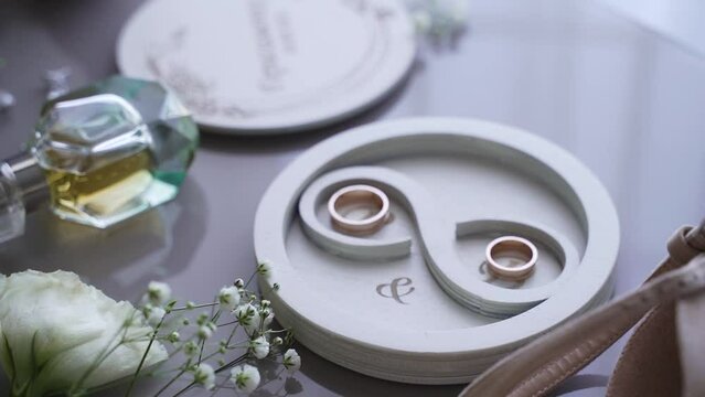 Round white wooden wedding ring box sits on mirrored table in hotel. Decorated packaging for gold training rings.