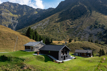 Fototapeta na wymiar A very unusual Swiss mountain chalet because it is black and made of wood. Around a beautiful green summer meadow