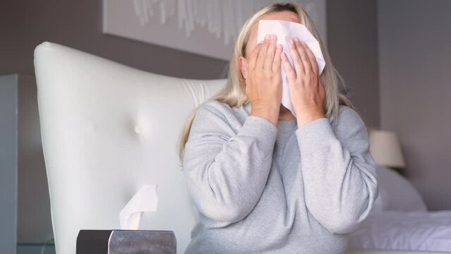 Young overweight woman sick and blowing her nose with napkins.