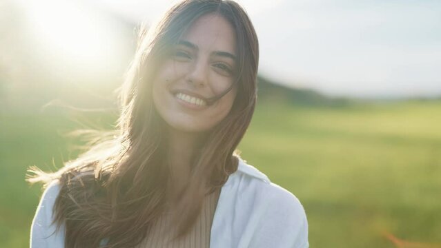 Video of beautiful young woman smiling while looking at camera while enjoying spring in a field.