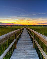 Fototapeta na wymiar wooden dock on the inlet at Pawleys Island in South Carolina in warm golden light at sunset