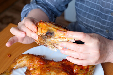 The hands of an elderly woman operate a grilled chicken