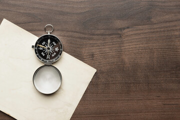 Top view of compass and old paper on the brown wooden table background.