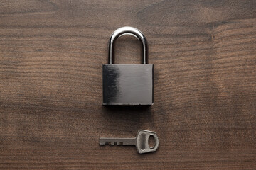 Padlock and key on the brown wooden table background