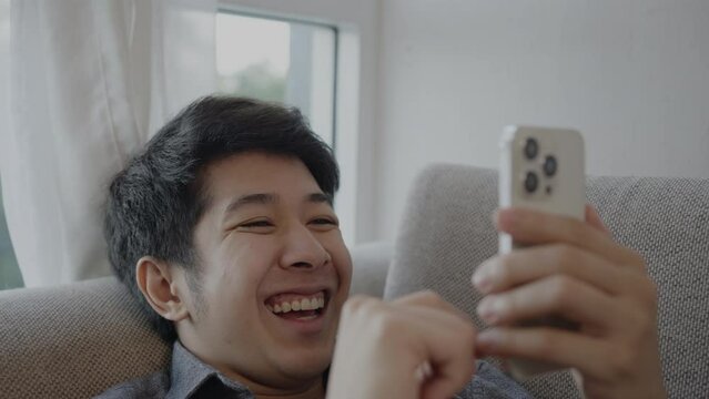 Man Laughs Happily at Humorous Video on Mobile, Enjoying a Good Laugh While Watching Funny Clip on Smartphone.