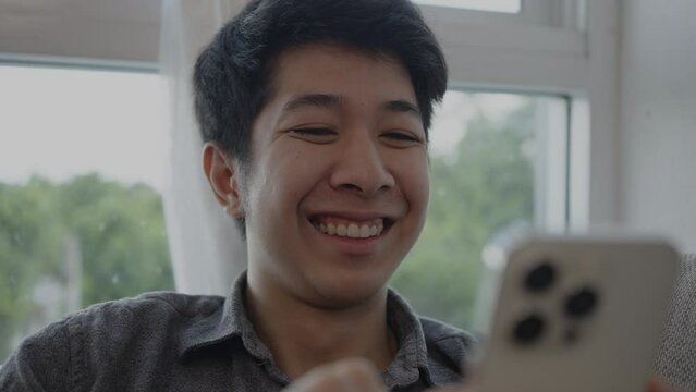 Smiling man Laughs Happily at Humorous Video on Mobile, Enjoying a Good Laugh While Watching Funny Clip on Smartphone.