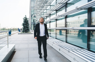 Confident businessman walking near glass wall