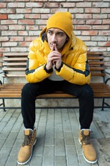 Fashionable handsome man sits on the bench in winter time