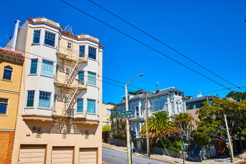 Pale yellow house with bay windows and fire escape off 15th street on blue sky day