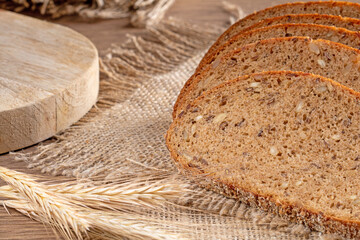 Slices of fresh rye bread with grains lie on a burlap napkin, close-up rustic style