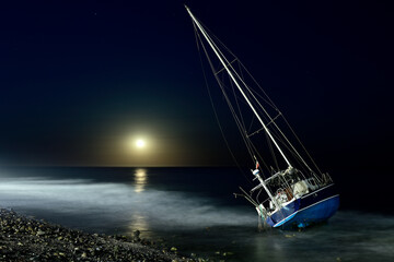 velero encallado en una playa de Marbella por la noche con la luna llena - obrazy, fototapety, plakaty