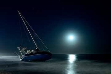 velero encallado en una playa de Marbella por la noche con la luna llena - obrazy, fototapety, plakaty