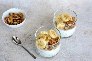 banana chia pudding with walnut and banana slices in drinking glasses 