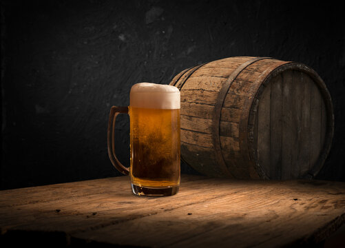 mug of beer, wheat ears, green hops and beer barrel on a wooden background. High quality photo