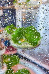 Water droplets on glass with blurry green plant in background