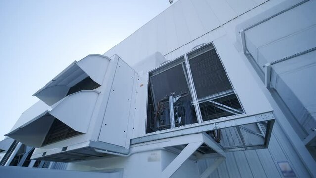 Large ventilation pipes on facade of commercial building. Outdoor split air conditioner units mounted on industrial building facade. Air conditioning system assembled on side of building
