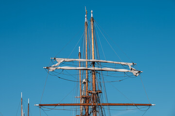 Collection of tall wooden sail masts against a bright blue sky.