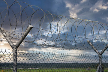 Security barrier with barbed wire fence on beautiful clouds and sky