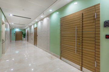 View of the corridor of a modern office with brown doors and light tile trim.