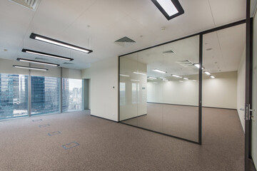 An open office space with white walls, panoramic windows and glass partitions.